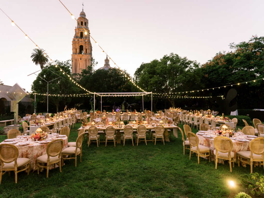 Garden wedding reception with floral linen tables and string lights, a luxury wedding planning production
